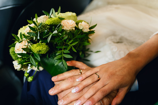 Wedding rings on the hands of newlyweds, bride's bouquet
