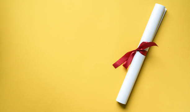 close up top view of certificated degree on yellow background for education concept close up top view of certificated degree on yellow background for education concept ceremony photos stock pictures, royalty-free photos & images