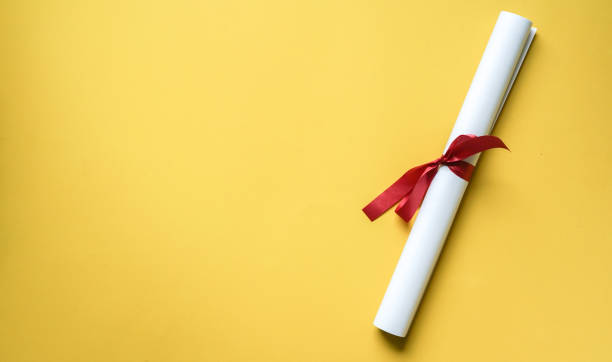 close up top view of certificated degree on yellow background for education concept close up top view of certificated degree on yellow background for education concept masters degree photos stock pictures, royalty-free photos & images