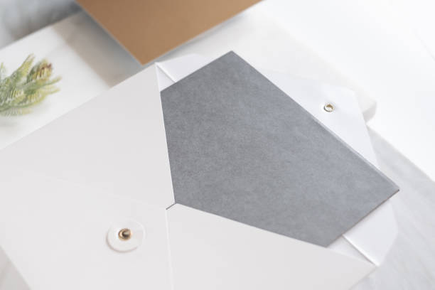 istock top perspective view of blank grey card in white envelop with pine leaf on two layer step of marble table top.Mock up template for display of design,modern business items. 1147240103