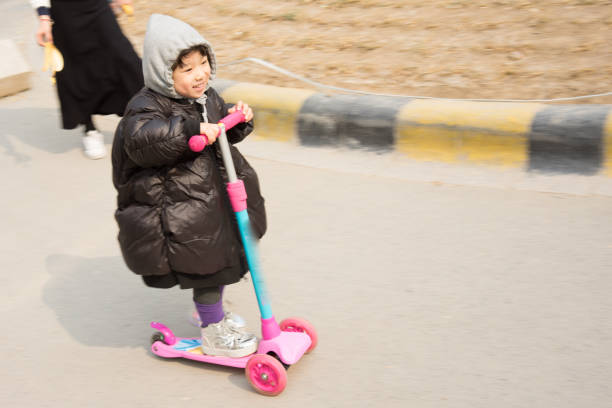 a little girl playing skate scooter in the garden