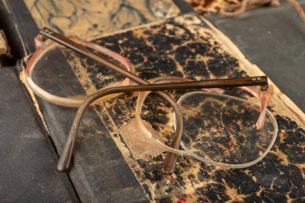 istock Broken frame from glasses. Old book and glasses. Dark background. 1147247715