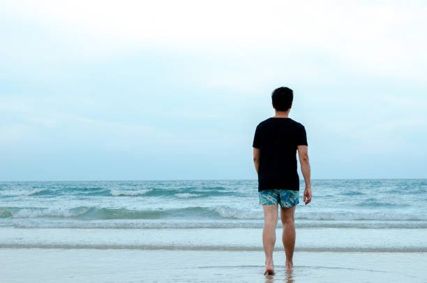 istock A lonely Asian man walking alone on beach 1147247842