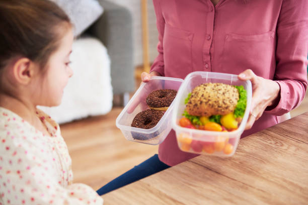 若い子供は健康的なサンドイッチとチョコレートドーナツの間に選択します - child human hand sandwich lunch box ストックフォトと画像