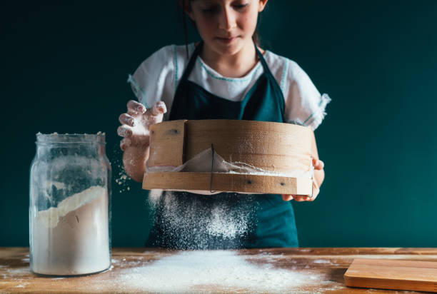 istock little girl sifting flour for dough 1147250142