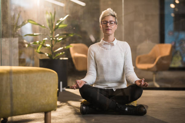 オフィスで蓮の位置で瞑想している若い実業家 - zen like meditating yoga business ストックフォトと画像