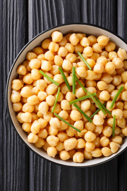 istock Organic snack boiled chickpeas close-up in a black bowl. Vertical top view 1147257584