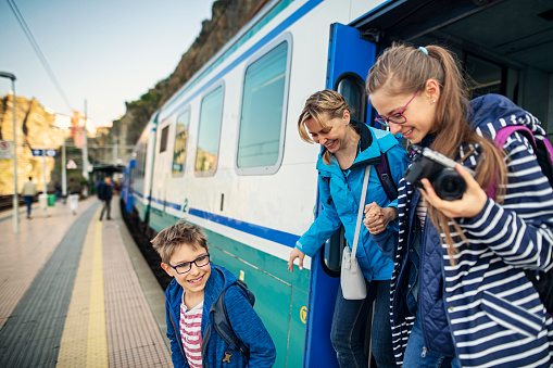Family getting out of train at the Manarola train station, Cinque Terre. Happy family is anxious to begin sighseeing of beautiful italian town.\nNikon D850