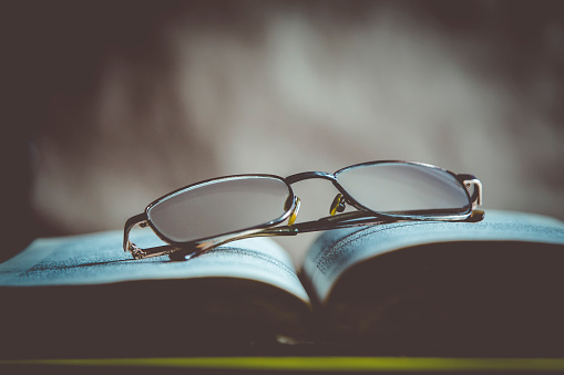 Reading a book after hard working day. Glasses on a book. Open book with glasses