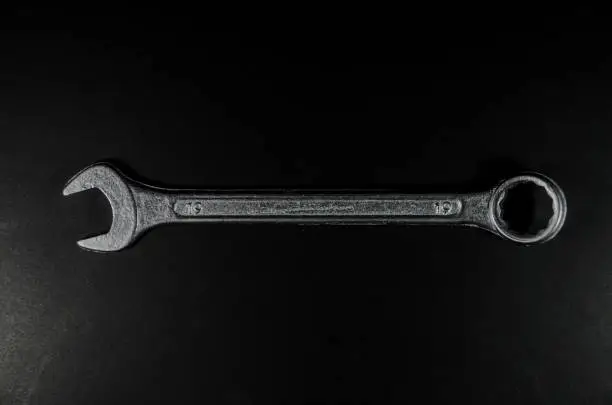 Photo of top view of a silver wrench on black background