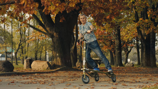 istock Fit senior riding slider scooter in park. Retirement activities 1147276751