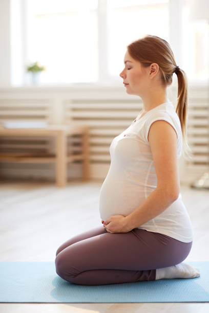 mujer embarazada haciendo ejercicios respiratorios - human pregnancy yoga exercising prenatal care fotografías e imágenes de stock