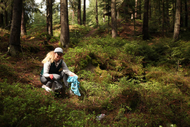 istock Woman cleans garbage and plastic in forest. Green volunteering. Caring for environment 1147279276