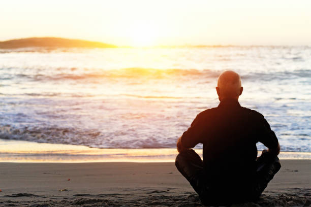istock Sitting cross-legged, a man meditates beside the sea 1147280214