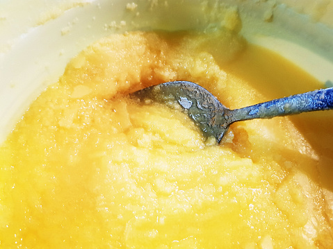 A spoon dips into a tub of ghee or clarified butter.