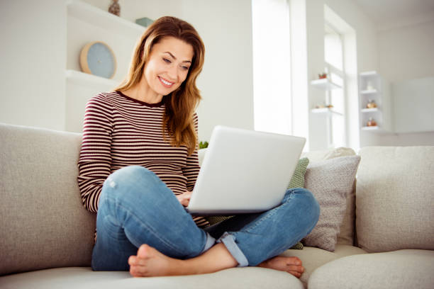 feche acima da foto bonita ela suas mãos da senhora braços da preensão do caderno fale dizer fale falar dizer skype parentes amigos usar jeans denim listrado pullover roupas sentar conforto acolhedor divan casa sala de estar dentro - skype - fotografias e filmes do acervo