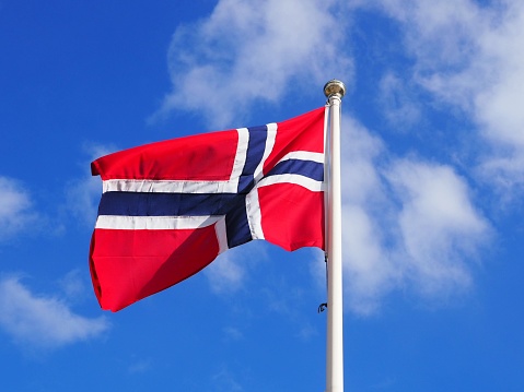 The Norwegian flag against a blue sky with clouds