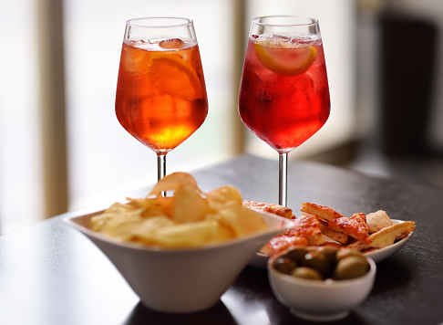 Italian aperitives/aperitif: glass of cocktail (sparkling wine with Aperol) and appetizer platter on the table. Traditional italian cuisine.