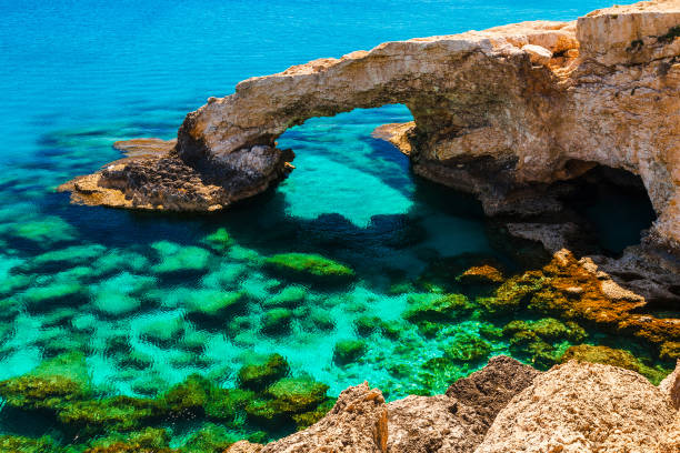 hermoso arco de roca natural cerca de ayia napa, cavo greco y protaras en la isla de chipre, mar mediterráneo. legendarios amantes del puente. increíble mar verde azul y día soleado. - headland fotografías e imágenes de stock