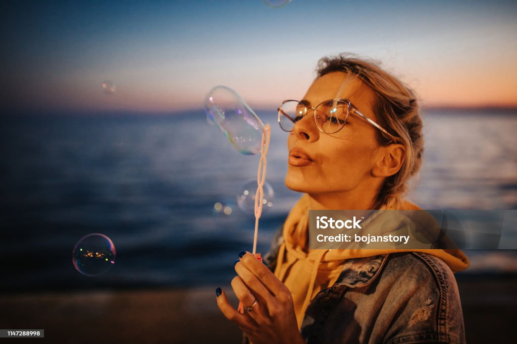 Junge Frau bläst Blasen am Meer - Lizenzfrei Abenddämmerung Stock-Foto