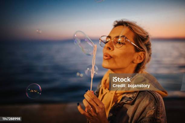 Junge Frau Bläst Blasen Am Meer Stockfoto und mehr Bilder von Abenddämmerung - Abenddämmerung, Attraktive Frau, Blase - Physikalischer Zustand