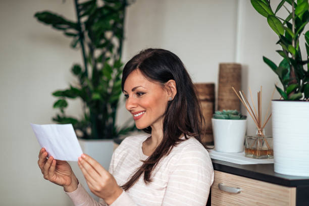 istock Cheerful woman looking at blank envelope at home.