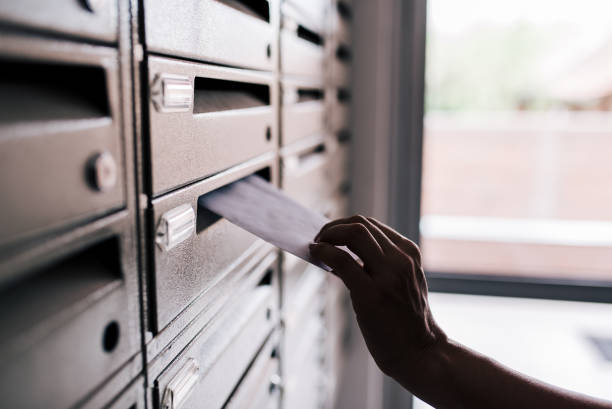 istock Inserting letter into a building metal mailbox, close-up. 1147289287