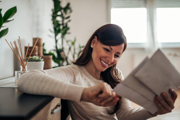 smiling woman looking at received mail at home, close-up. - opening mail letter envelope imagens e fotografias de stock