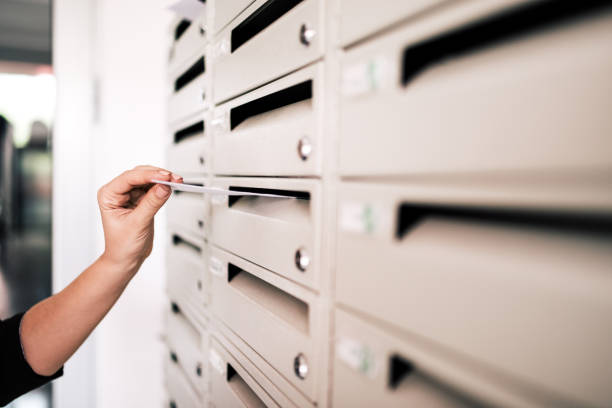 postkarte versenden. nahaufnahme der hand der frau, die einen brief veröffentlicht. - briefkasten stock-fotos und bilder