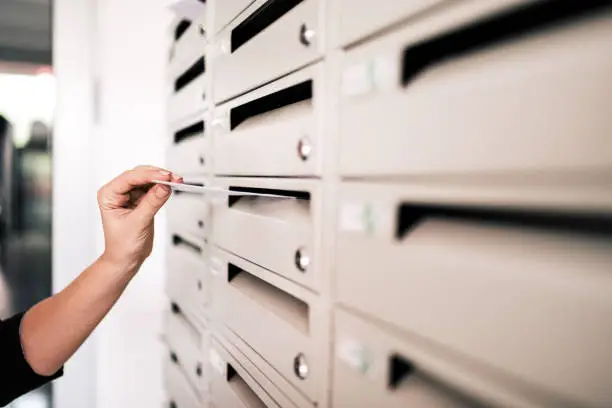 Sending postcard. Close-up of woman's hand posting a letter.