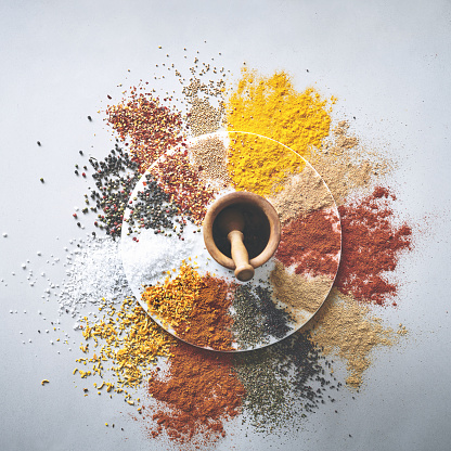 Shot of a pestle and mortar with an assortment of spices scattered around it