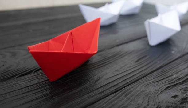 istock Leadership concept. Red leader paper ship leading among white. 1147292244