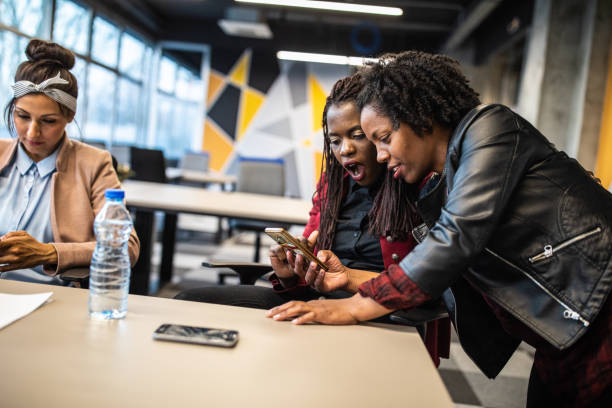 istock Multi-ethnic group of female friends using phone at work 1147292629
