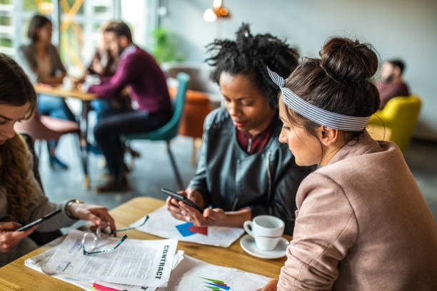 istock Three multi-ethnic female friends using phone in cafe 1147292820