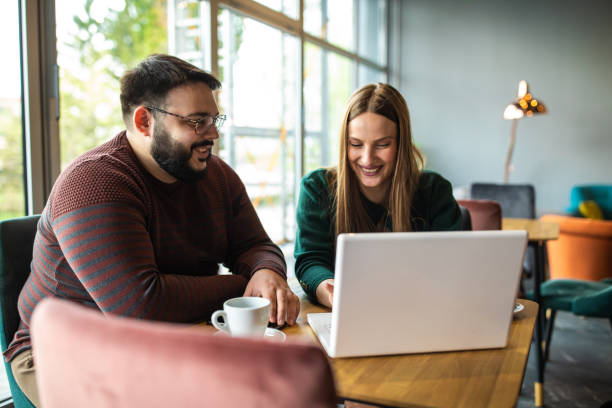 istock Happy coworkers using laptop in internet cafe 1147294033