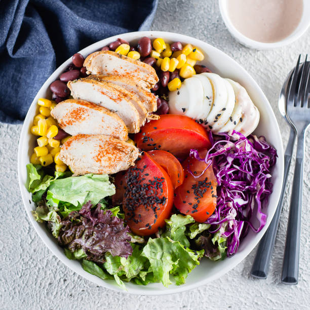 istock Healthy lunch salad with chicken, egg, tomatoes, lettuce, corn, red beans, red cabbage and barbeque sauce on light concrete background. Dietary menu, clean eating. Flat lay, top view, square image 1147294243