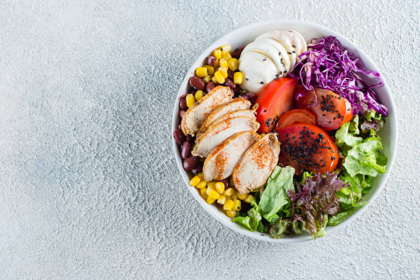 istock Healthy lunch salad with chicken, egg, tomatoes, lettuce, corn, red beans, red cabbage and barbeque sauce on light concrete background. Dietary menu. Flat lay, top view 1147294338