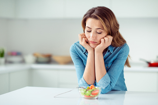 Close-up portrait of her she nice lovely charming attractive sad bored dull disappointed brown-haired lady looking at new green detox vitamin salad in light white interior style kitchen.