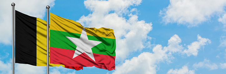 Belgium and Myanmar flag waving in the wind against white cloudy blue sky together. Diplomacy concept, international relations.
