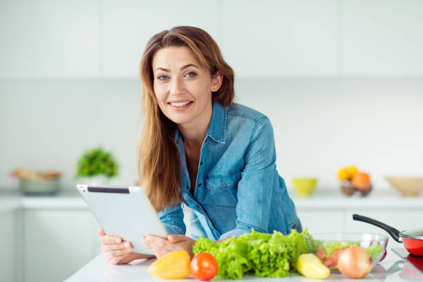 retrato do close-up dela ela agradável adorável atraente alegre inteligente castanho-haired senhora lendo online internet livro literatura culinária gastronomia jantar almoço delicadeza em luz branca interior estilo cozinha - smart casual occupation casual healthy eating - fotografias e filmes do acervo