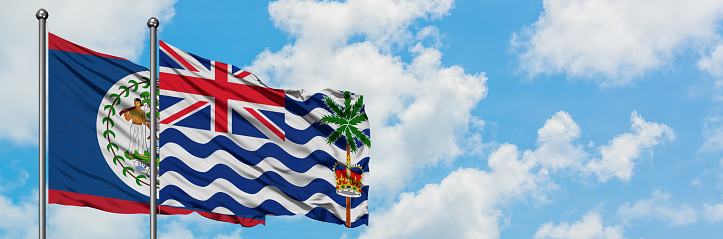 Belize and British Indian Ocean Territory flag waving in the wind against white cloudy blue sky together. Diplomacy concept, international relations.