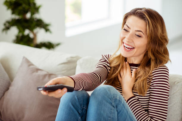 istock Close up side profile photo beautiful she her lady remote controller hands arms laughing loud change channels comic serial wear striped pullover clothes sit comfort divan house living room indoors 1147296212