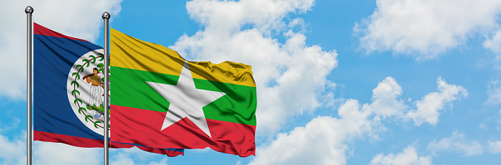 Belize and Myanmar flag waving in the wind against white cloudy blue sky together. Diplomacy concept, international relations.