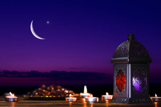 The Muslim feast of the holy month of Ramadan Kareem. Beautiful background with a shining lantern, dates on the tray against the night sky with stars and Crescent moon. Free space for your text stock photo