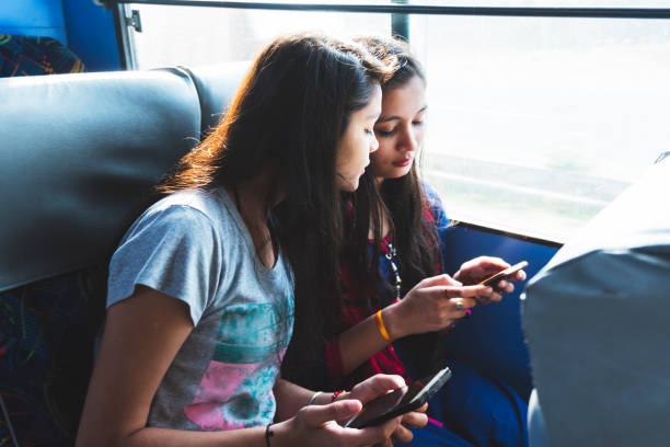 dos amigos viajan en el autobús y utilizan el teléfono inteligente - travel teenager talking student fotografías e imágenes de stock