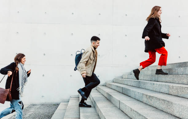 friends running up steps in urban setting Three young friends running up on stone stairs climbing staircase stock pictures, royalty-free photos & images