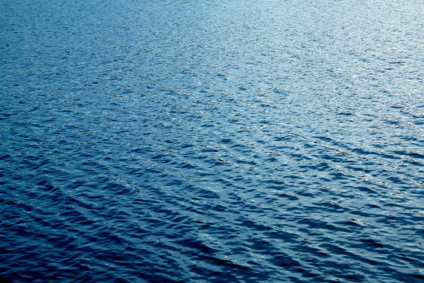 Beautiful deep blue lake water surface sun glare background texture stock photo