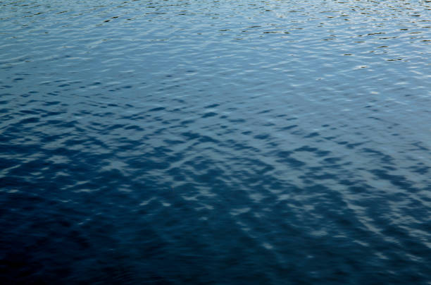 Beautiful deep blue lake water surface sun glare background texture stock photo