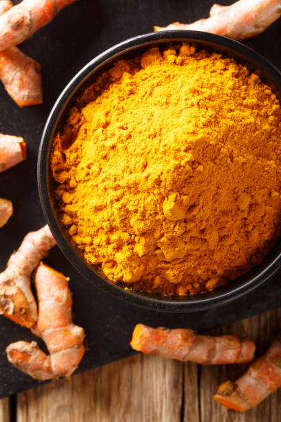 istock Ground fresh turmeric in a bowl and root close-up. Vertical top view 1147306315