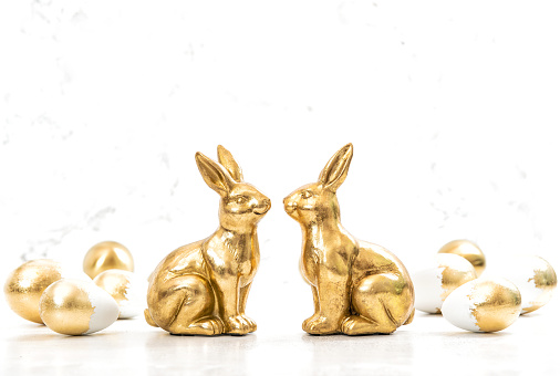 Golden bunnies with Easter eggs on white background